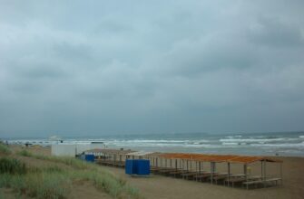 Пустой пляж Анапы, волны и низкие тучи во время летнего ненастья